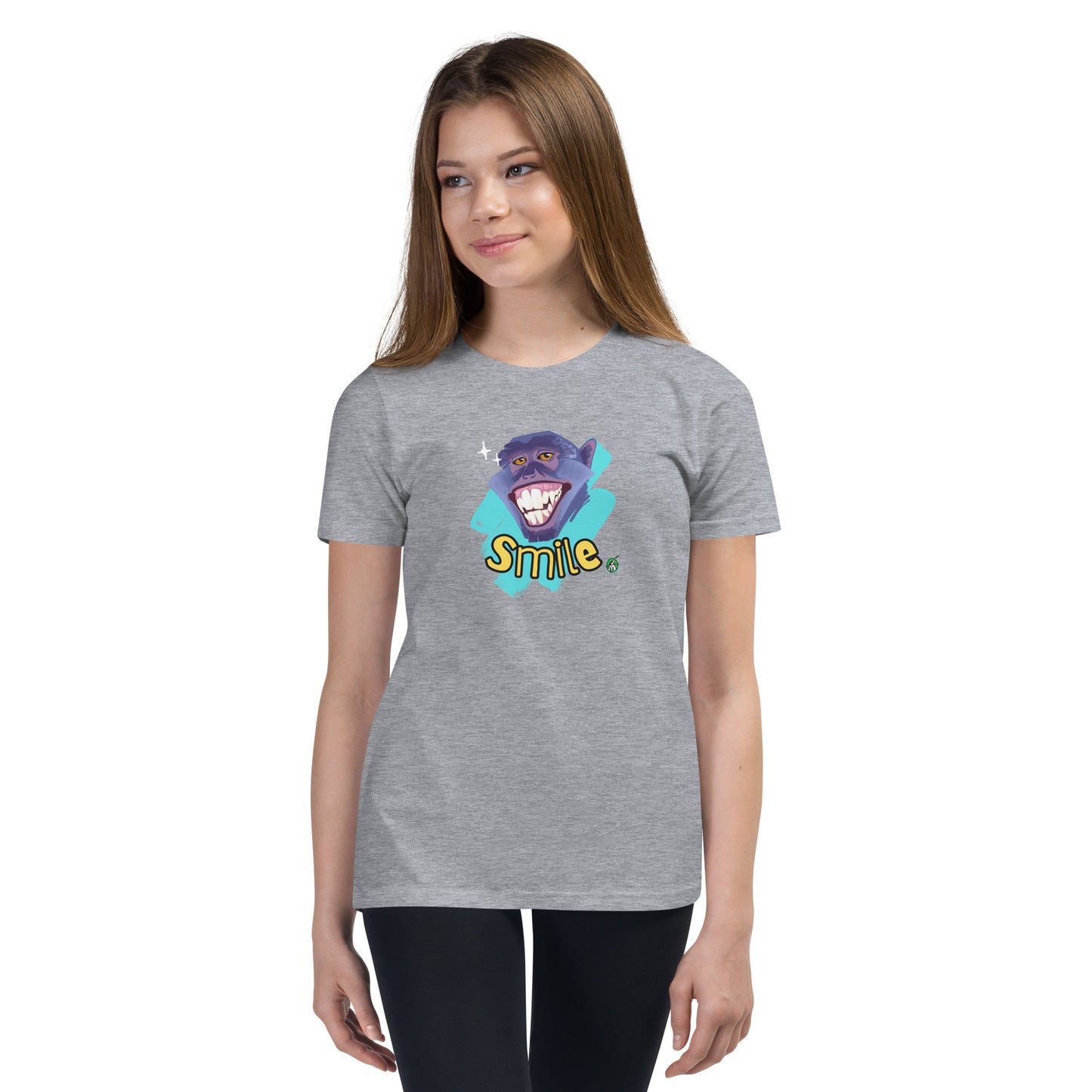 A girl standing wearing a grey kids t-shirt with the printed graphic of a smiling monkey and the word, Smile. Designed by Wizard Prints