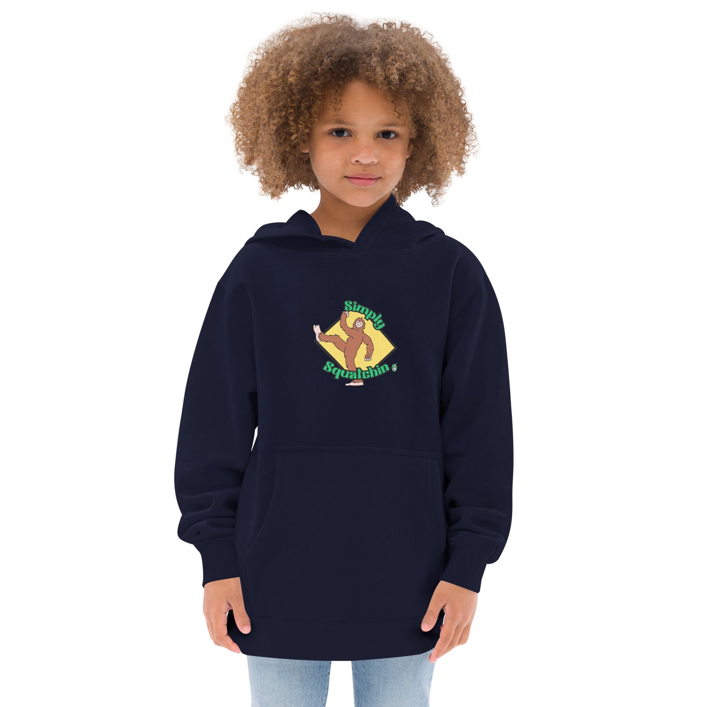 A girl standing wearing a navy blue kids graphic hoodie with a brown sasquatch and the statement, Simply Squatchin on a yellow background, by Wizard Prints