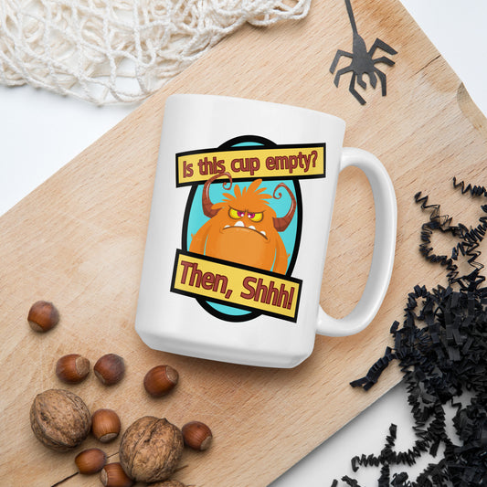 White Wizard Prints funny mug with cartoon monster and 'Is this cup empty? Then Shhh!' text on a wooden board with nuts and spider decorations.