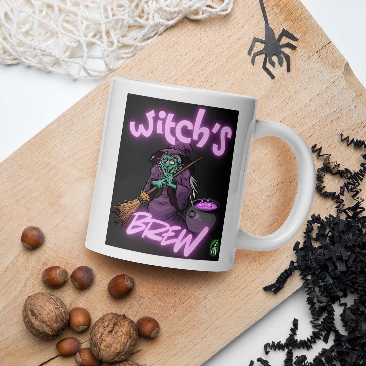 Wizard Prints mug with witch graphic and 'Witch's Brew' text on a wooden board with nuts and spider decorations.