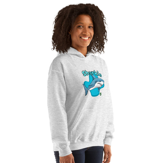 A woman standing wearing an ash hoodie with a printed graphic of a cartoon shark and the word, Sharkie. Designed by Wizard Prints.