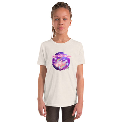 A girl standing wearing a creamy kids graphic tee shirt with dreamy purple cirlcle and the word Dreamer by Wizard Prints
