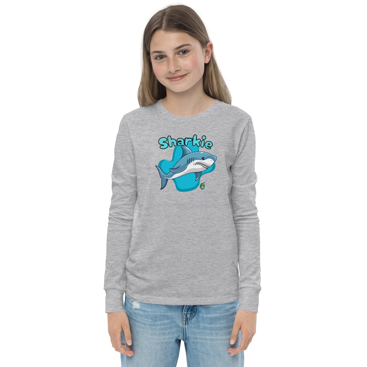 A girl standing and wearing a grey long sleeve t-shirt with a printed graphic of a shark and the word, 'Sharkie'. Designed by Wizard Prints