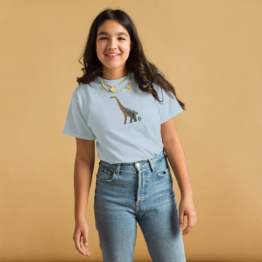 A girl standing and wearing a light blue t-shirt featuring a printed graphic of a life like brachiosaurus, designed by Wizard Prints.
