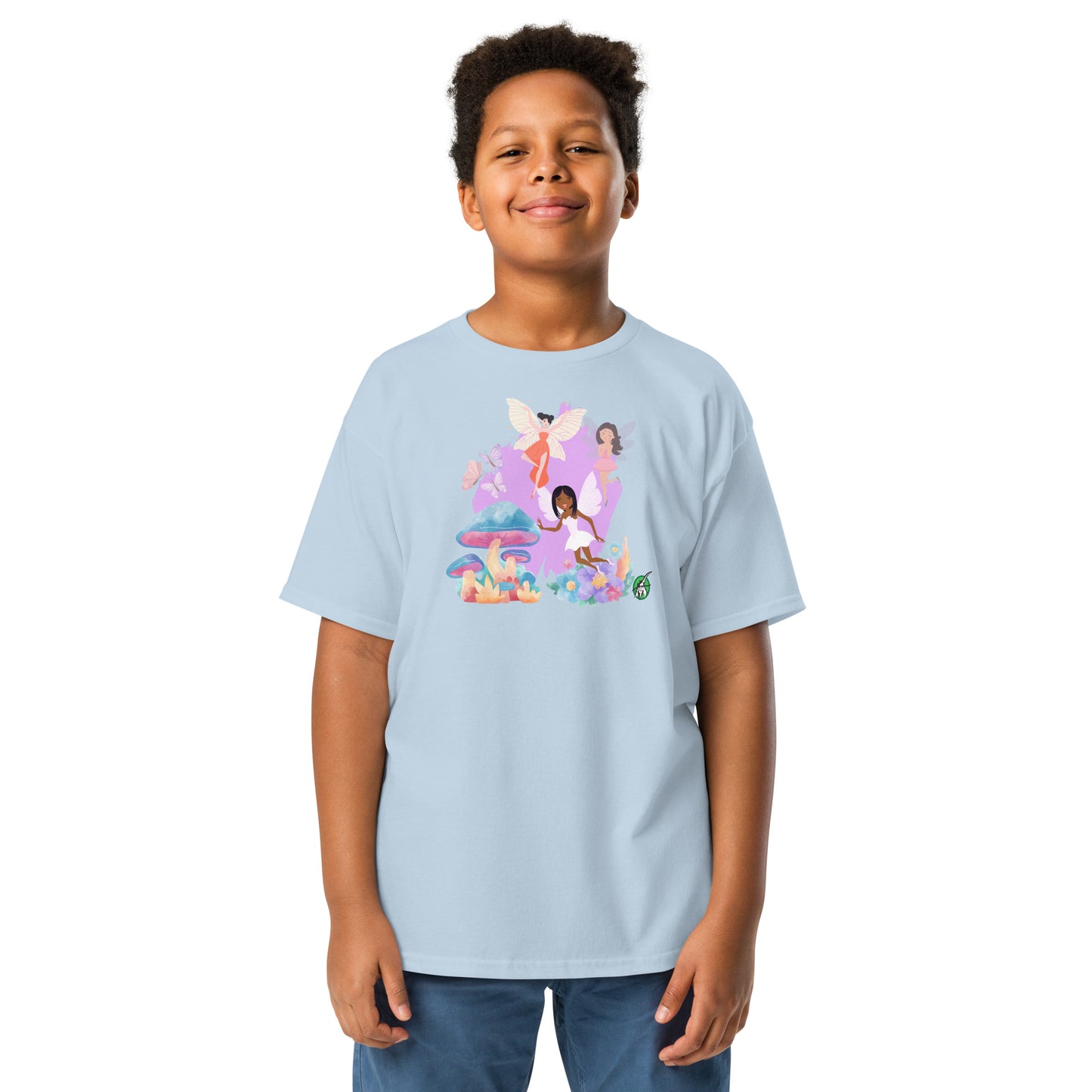 A boy standing and wearing a light blue t-shirt featuring a printed graphic of fairies flying over mushrooms, designed by Wizard Prints.