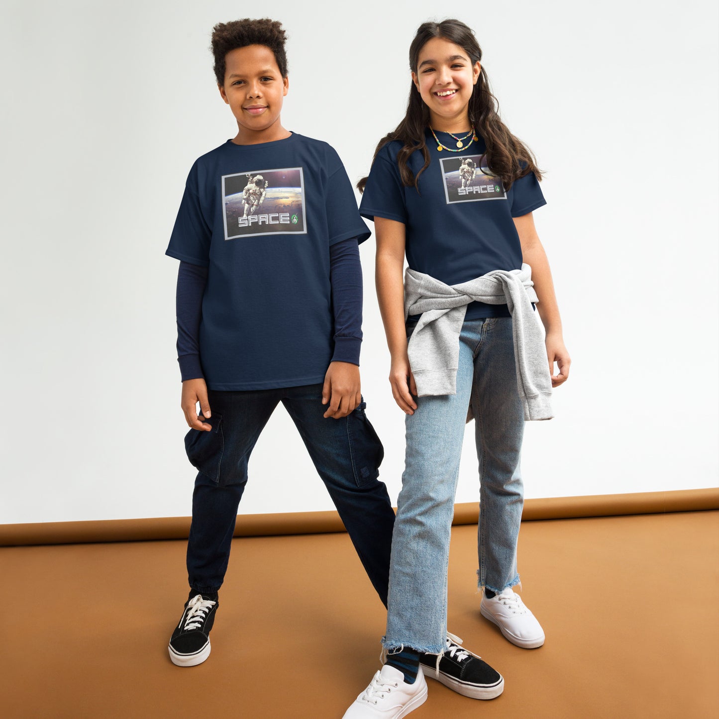 A boy and a girl standing and wearing navy blue t-shirts featuring a printed graphic of a real astronaut in space and the word, Space, designed by Wizard Prints.