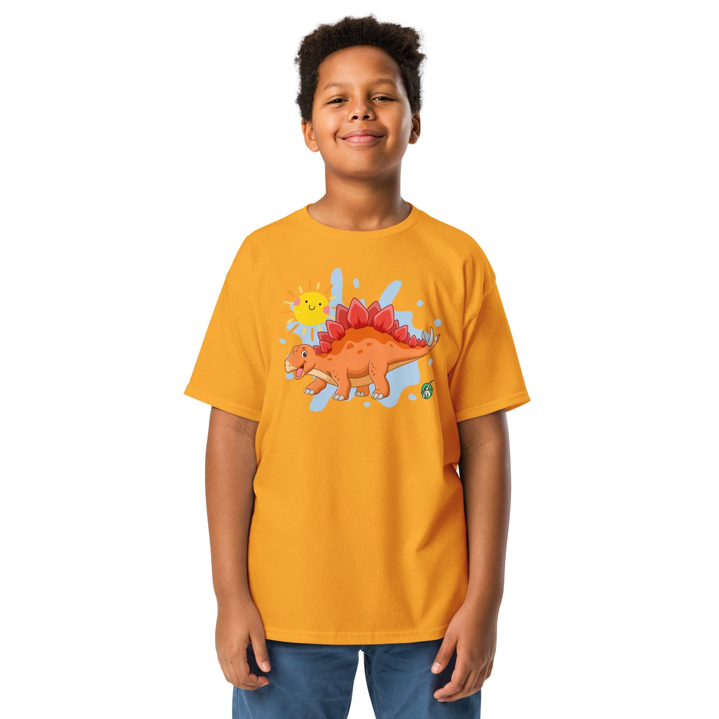 A boy standing and wearing an orange t-shirt with a printed graphic of a smiling cartoon Stegosaurus and the sun. Designed by Wizard Prints.