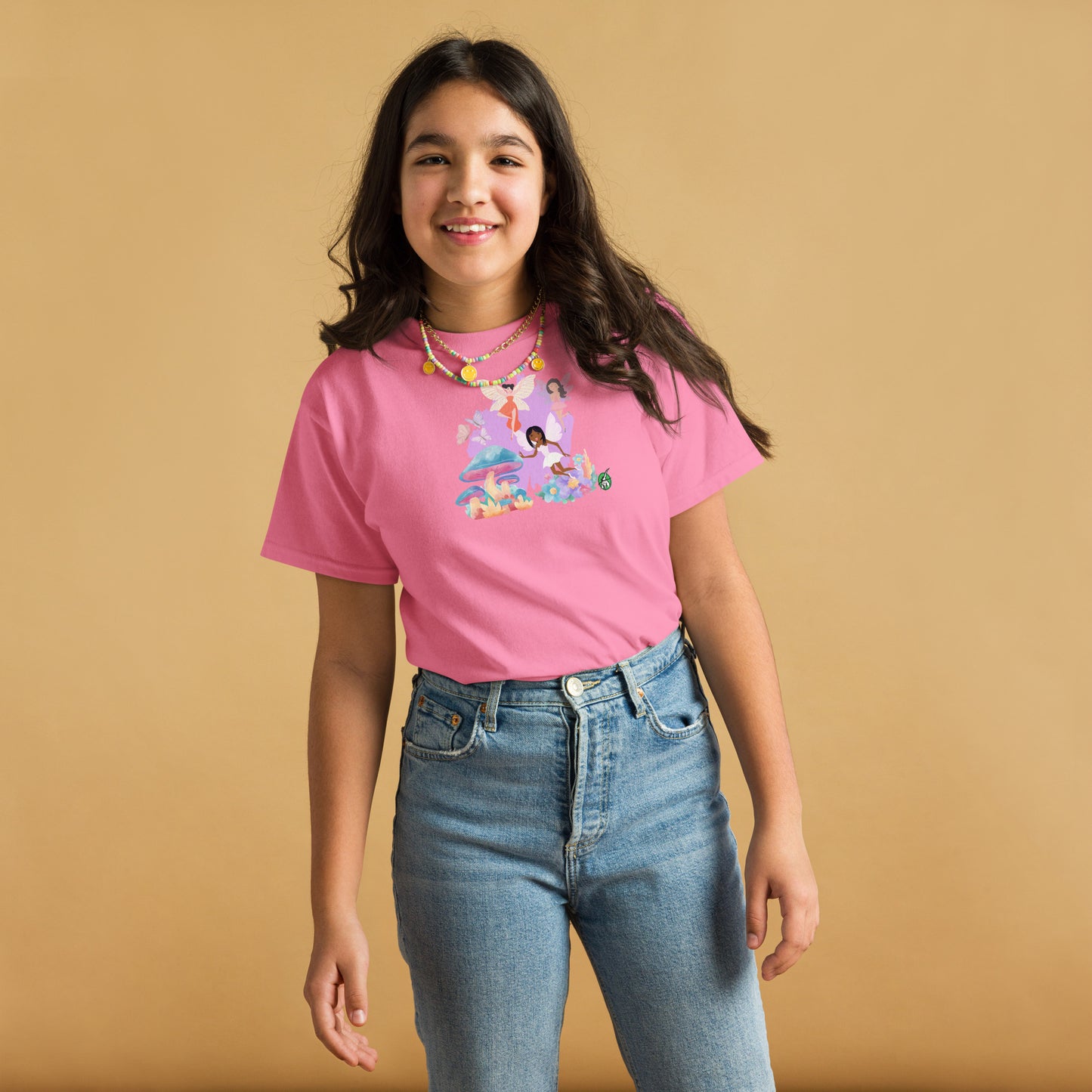 A girl standing and wearing a pink t-shirt featuring a printed graphic of fairies flying over mushrooms, designed by Wizard Prints.