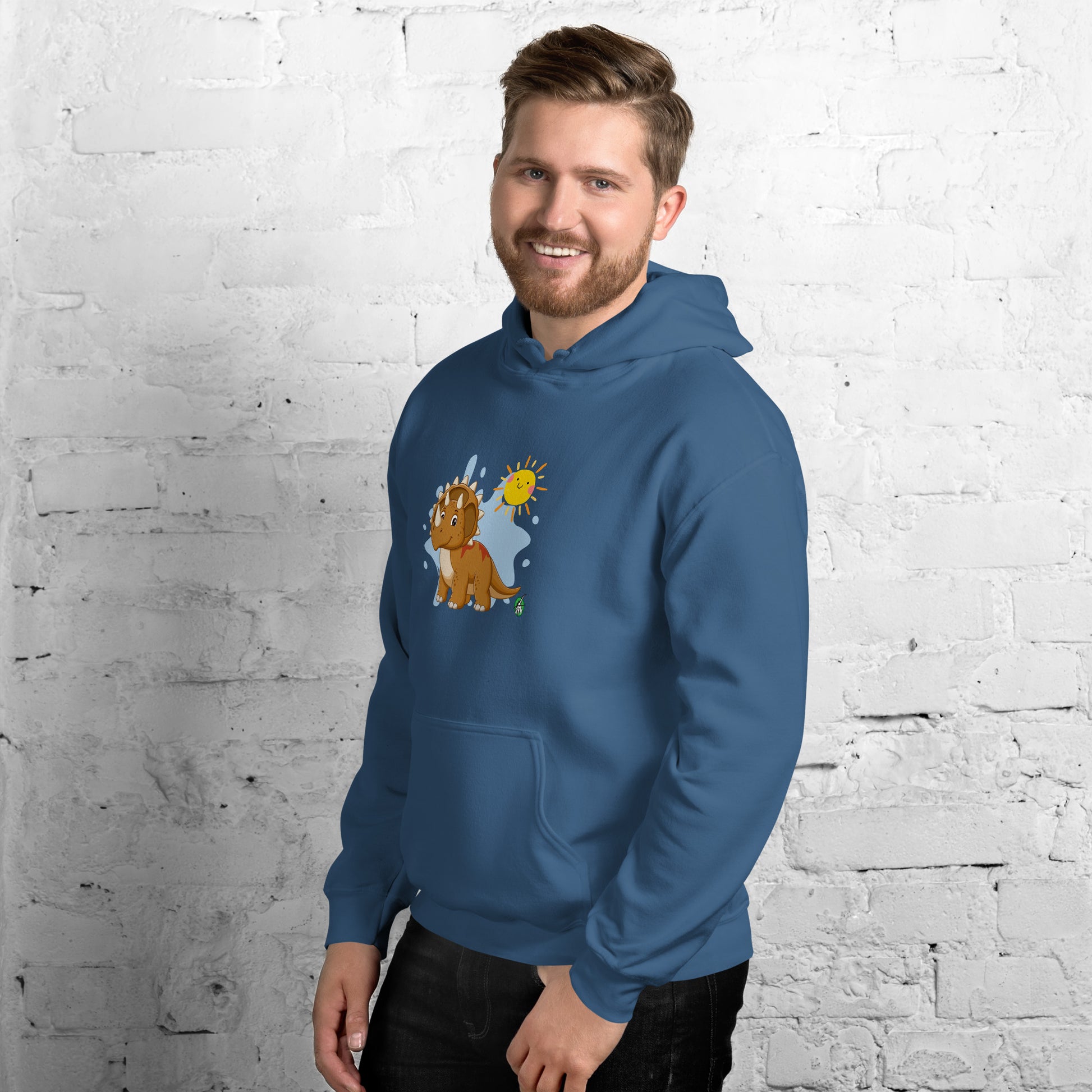 A man standing wearing an indigo hoodie with a printed graphic of a smiling cartoon dinosaur and the sun. Designed by Wizard Prints