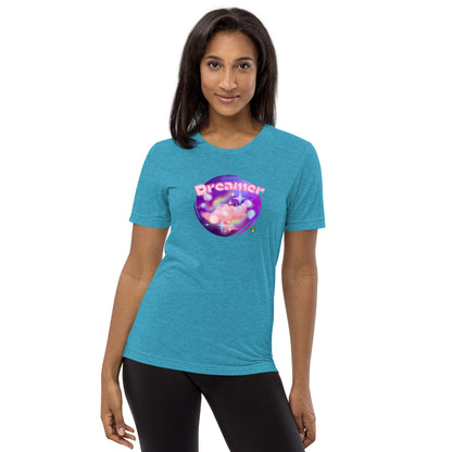 A woman standing wearing an aqua blue tee shirt with a printed graphic of a galaxy background and the word Dreamer on top. Designed by Wizard Prints