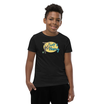 A boy standing wearing a black graphic tee shirt with a funny graphic on the front of a monkey hanging from the tree branch saying, Let's Hang by Wizard Prints and jeans on a white background
