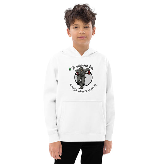 A boy standing wearing a white kids graphic hoodie with a ninja and the words I wanna be a ninja when I grow up, by Wizard Prints