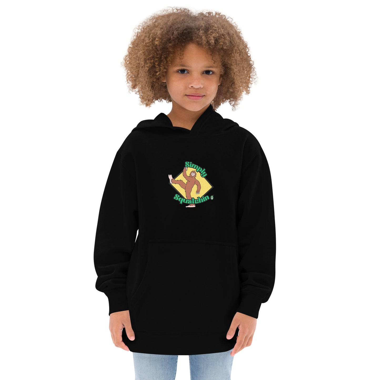 A girl standing wearing a black kids graphic hoodie with a brown sasquatch and the statement, Simply Squatchin on a yellow background, by Wizard Prints