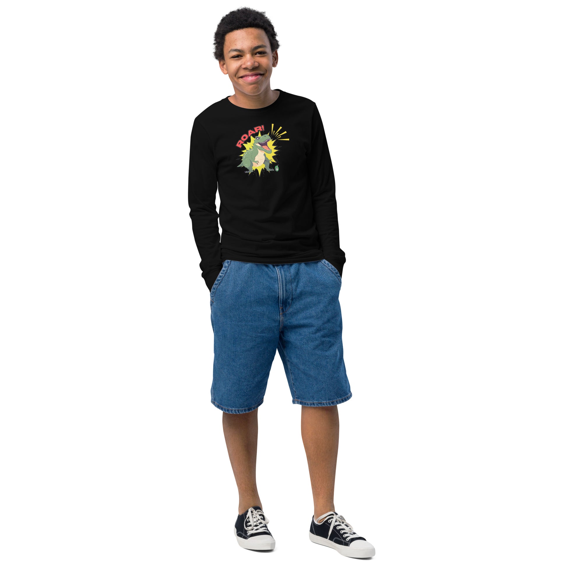 A boy standing and wearing a black long sleeve t-shirt with a printed graphic of a green roaring dinosaur and the word "Roar!", by Wizard Prints.