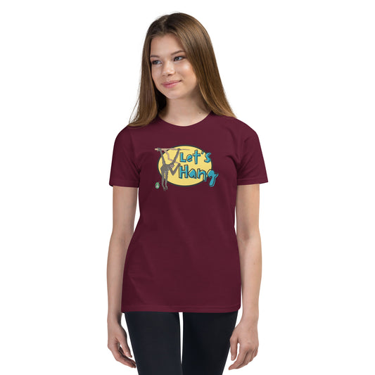 A girl standing wearing a dark red graphic tee shirt with a funny graphic on the front of a monkey hanging from the tree branch saying, Let's Hang by Wizard Prints and jeans on a white background
