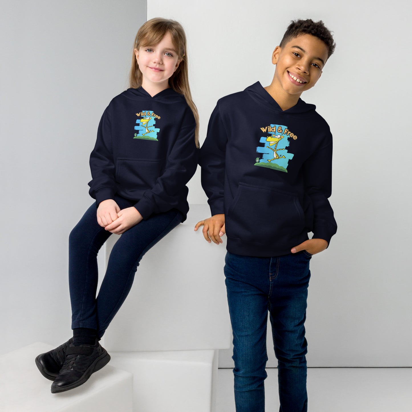 A boy and girl wearing a Wizard Prints kids hoodie in navy with a printed graphic on the front of a giraff with the words, Wild and Free.