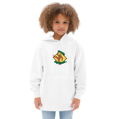 A girl standing wearing a white kids graphic hoodie with a brown sasquatch and the statement, Simply Squatchin on a yellow background, by Wizard Prints