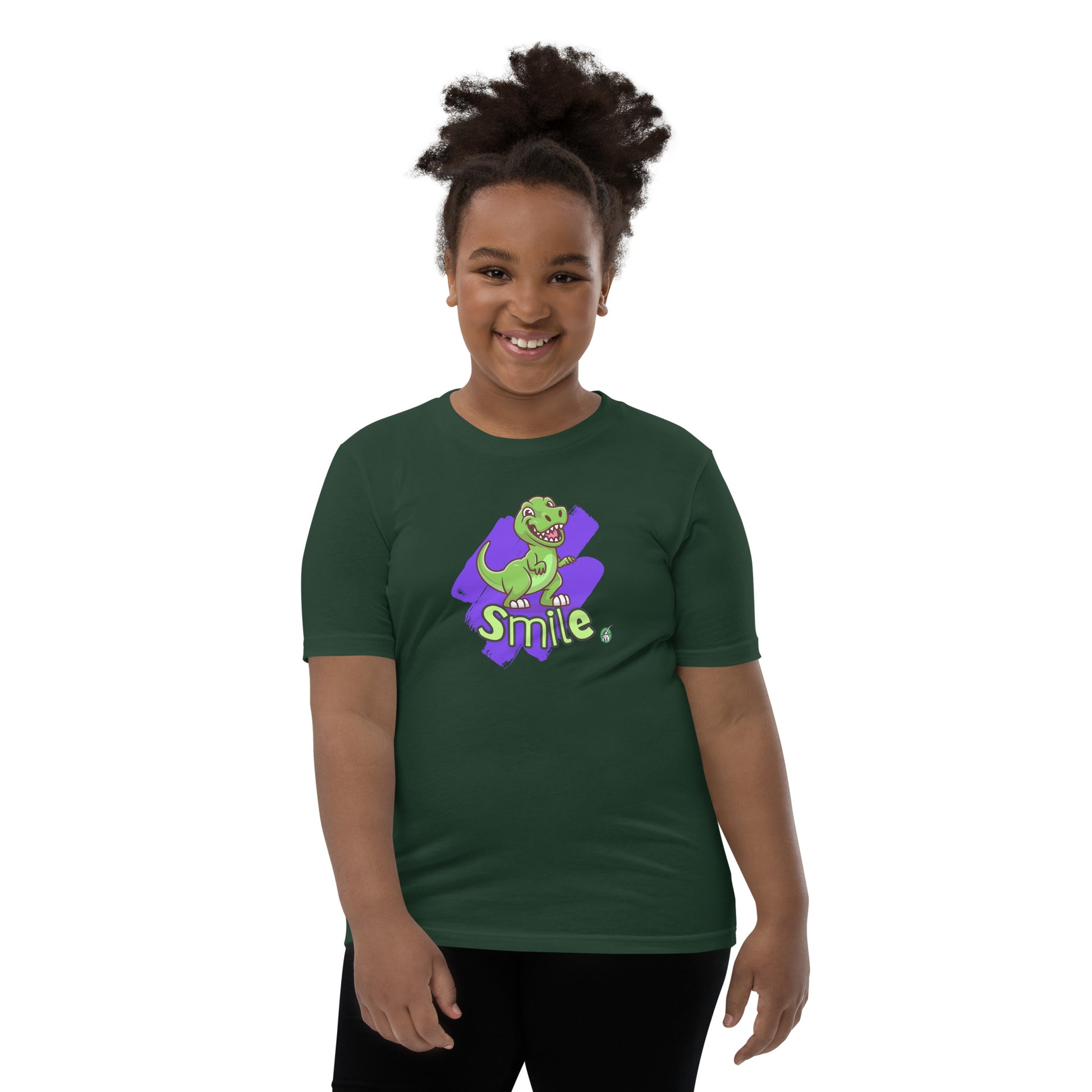  A girl standing wearing a forest green kids t-shirt with the printed graphic of a cartoon dinosaur and the word, Smile. Designed by Wizard Prints
