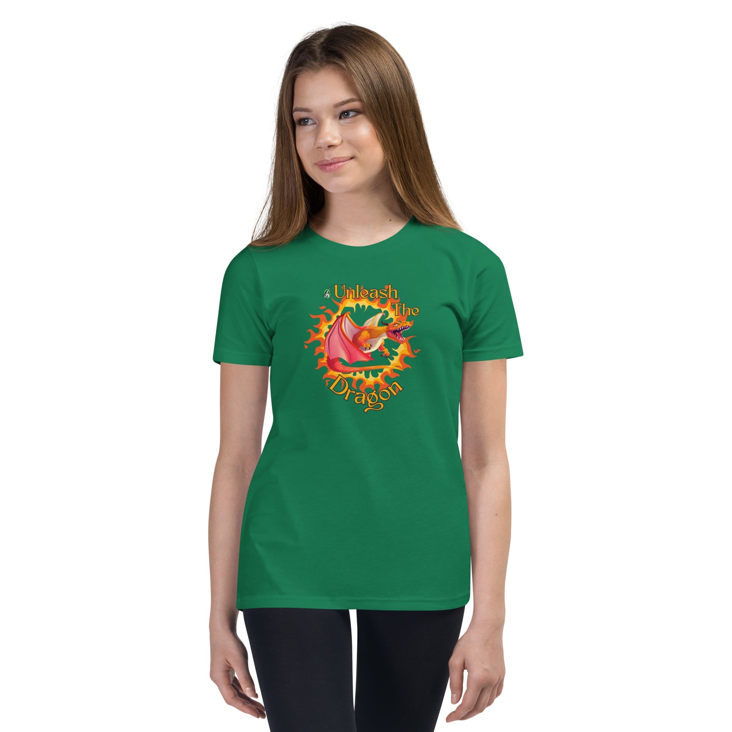  A girl standing wearing a green kids t-shirt with the printed graphic of a fire-breathing dragon with the statement, Unleash the Dragon. Designed by Wizard Prints