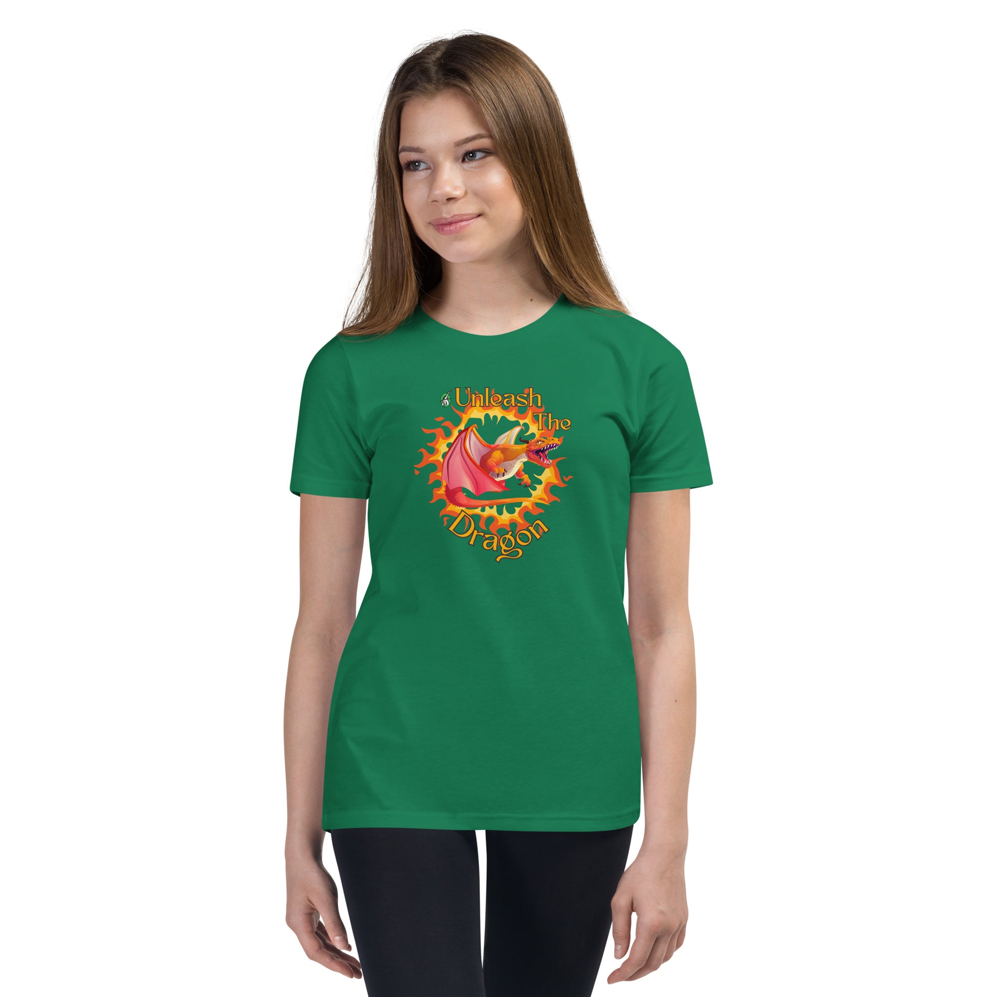  A girl standing wearing a green kids t-shirt with the printed graphic of a fire-breathing dragon with the statement, Unleash the Dragon. Designed by Wizard Prints