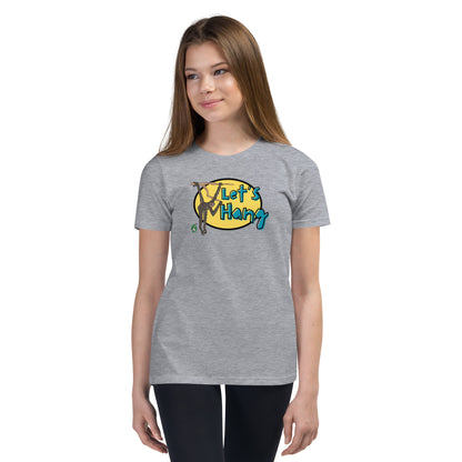 A girl standing wearing a grey graphic tee shirt with a funny graphic on the front of a monkey hanging from the tree branch saying, Let's Hang by Wizard Prints and jeans on a white background
