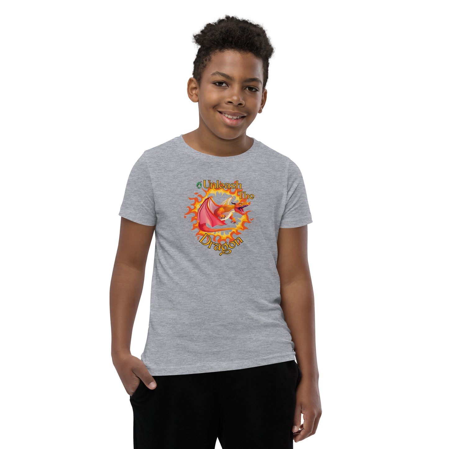  A boy standing wearing a grey kids t-shirt with the printed graphic of a fire-breathing dragon with the statement, Unleash the Dragon. Designed by Wizard Prints