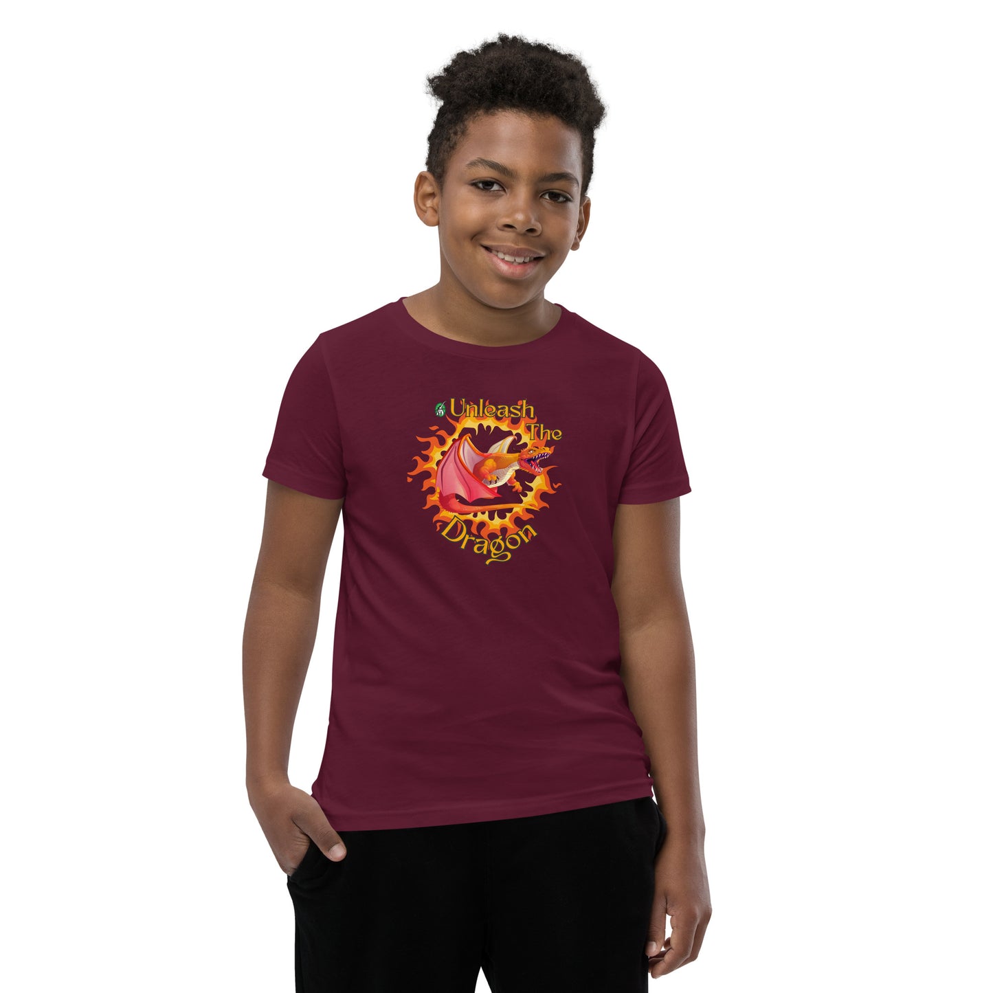 A boy standing wearing a maroon kids t-shirt with the printed graphic of a fire-breathing dragon with the statement, Unleash the Dragon. Designed by Wizard Prints