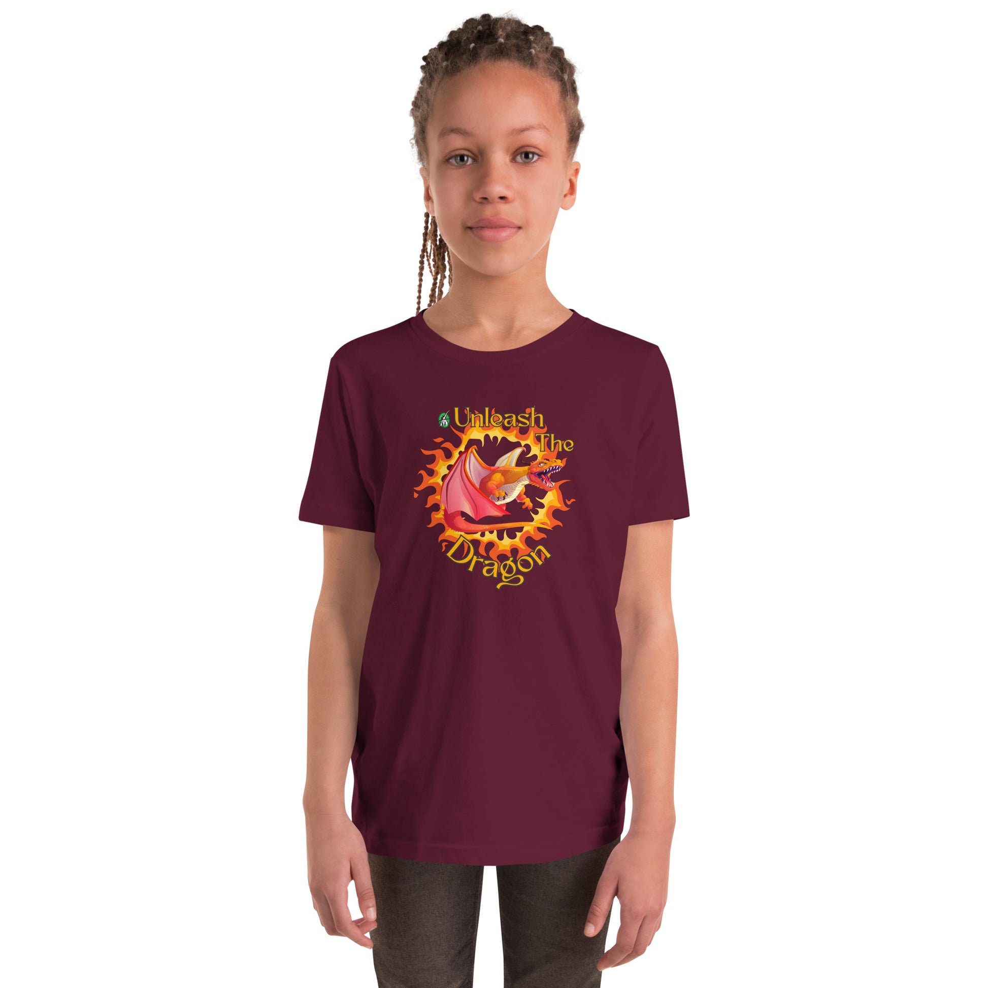  A girl standing wearing a maroon kids t-shirt with the printed graphic of a fire-breathing dragon with the statement, Unleash the Dragon. Designed by Wizard Prints