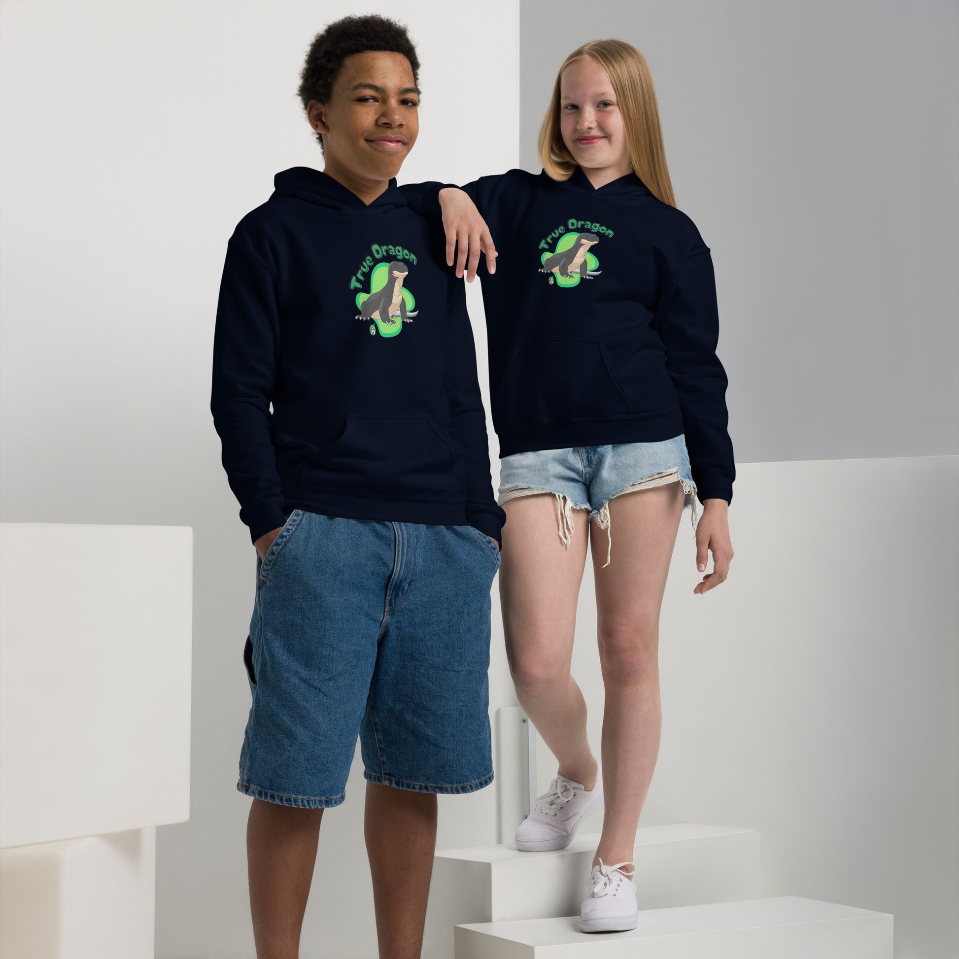 A boy and girl wearing a Wizard Prints kids hoodie in navy with a printed graphic on the front of a dragon with the words True Dragon