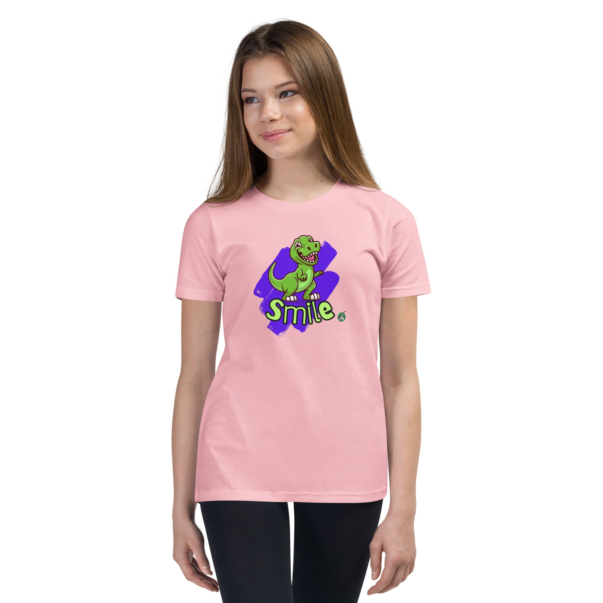  A girl standing wearing a pink kids t-shirt with the printed graphic of a cartoon dinosaur and the word, Smile. Designed by Wizard Prints