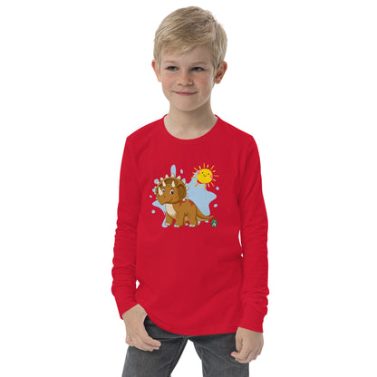 A boy standing wearing a red long sleeve t-shirt with a printed graphic of a smiling triceratops and the sun. Designed by Wizard Prints.