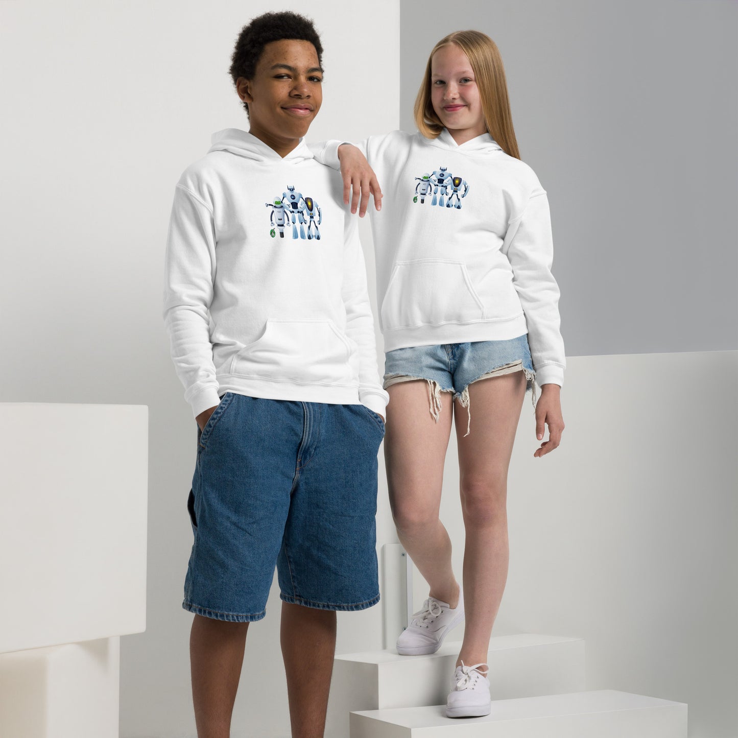 A boy and girl wearing a Wizard Prints kids hoodie in white with a printed graphic on the front of a group of robots