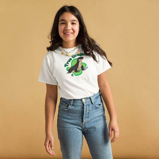 A girl standing and wearing a white t-shirt featuring a printed graphic of a komodo dragon and the words, True Dragon. Designed by Wizard Prints.