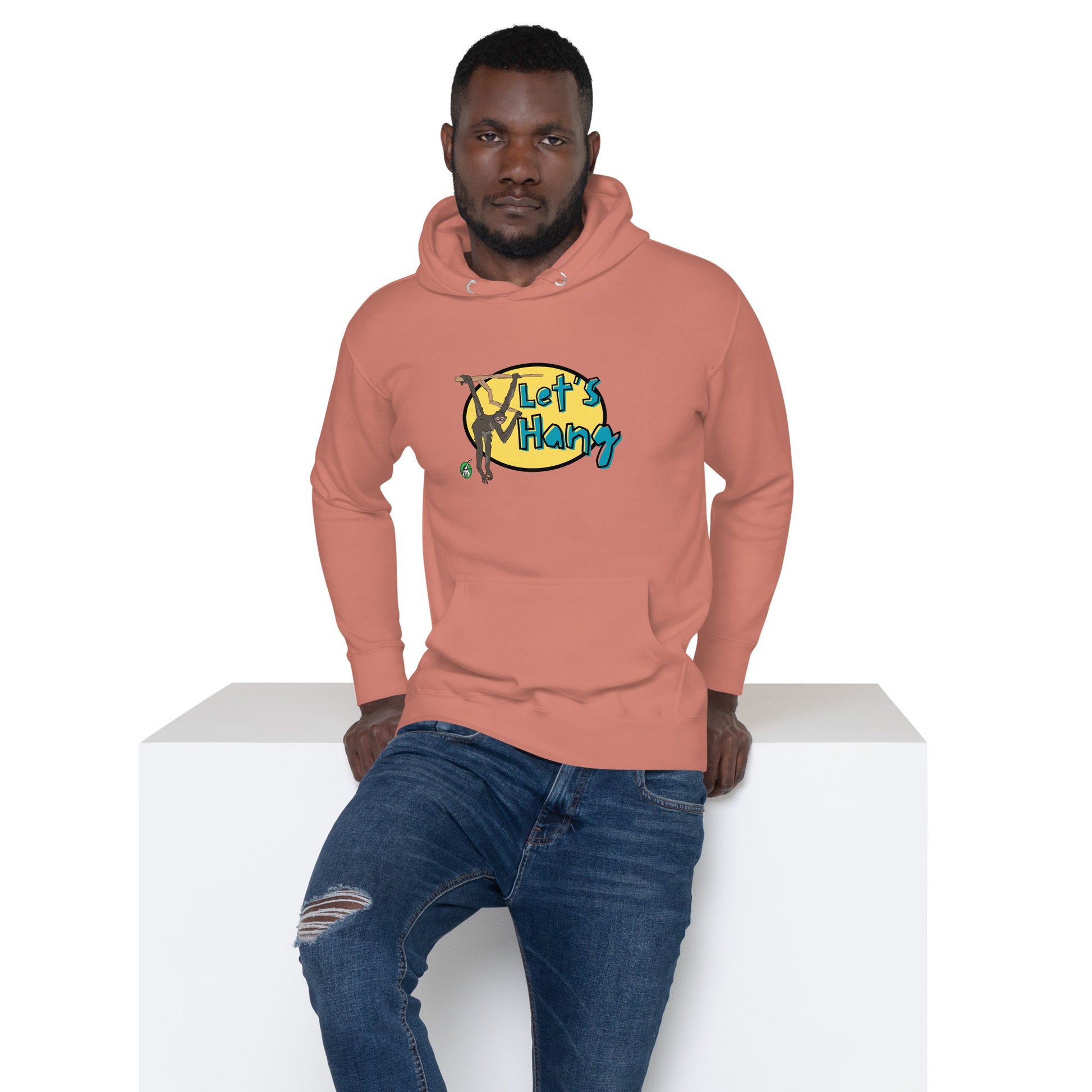 A man standing wearing dusty rose hoodie with a printed graphic of a monkey hanging on a branch with the words, Let's Hang. Designed by Wizard Prints.