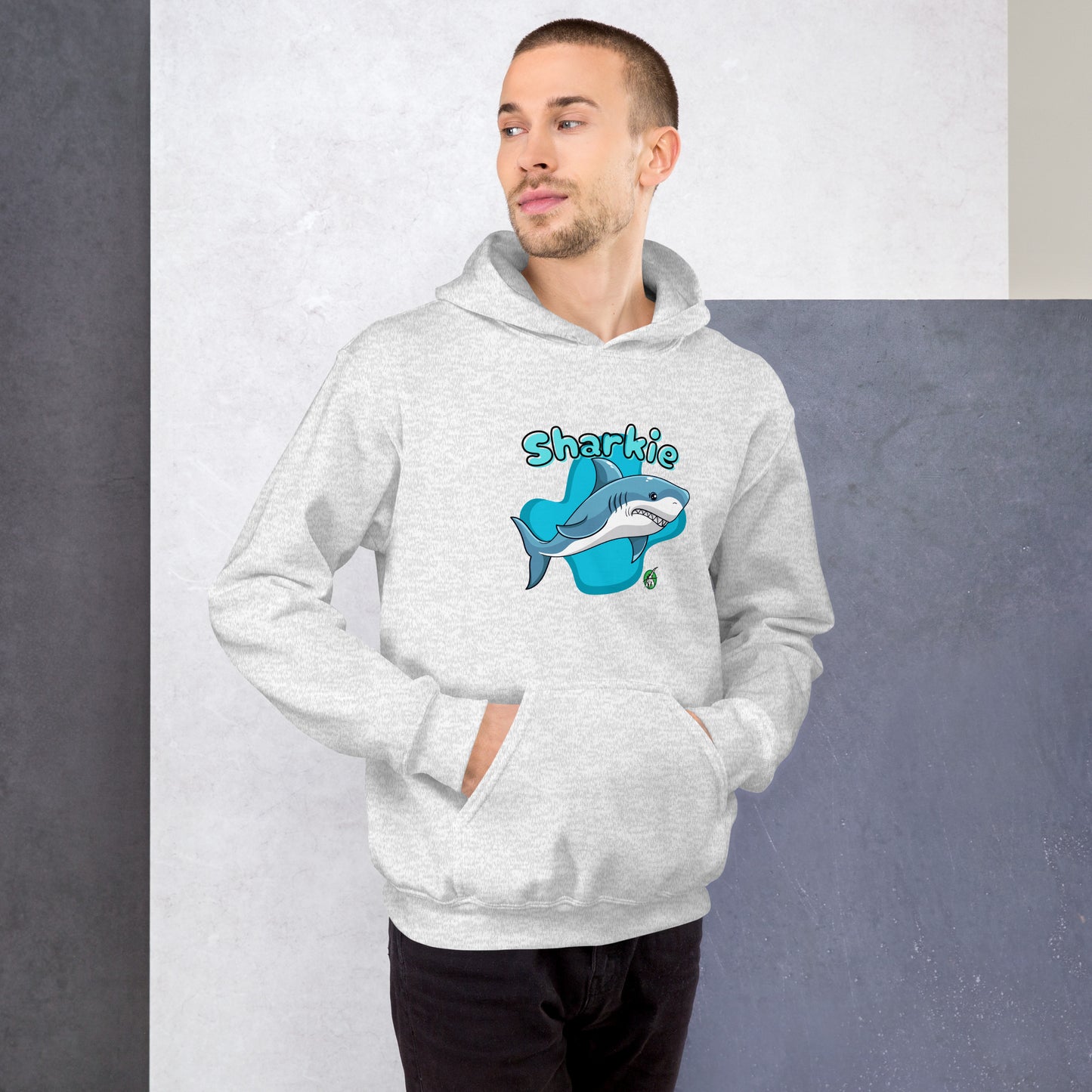 A man standing wearing an ash hoodie with a printed graphic of a cartoon shark and the word, Sharkie. Designed by Wizard Prints.