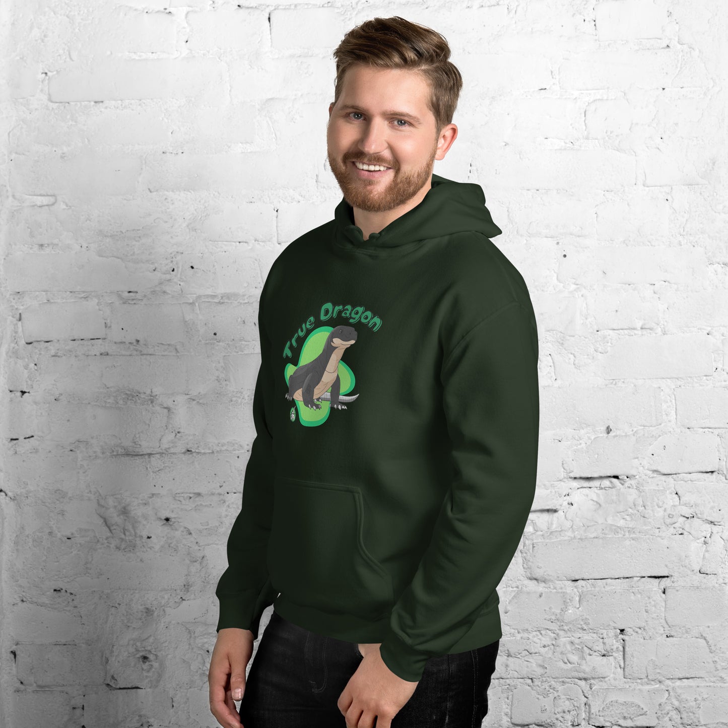 A man standing wearing a forest green hoodie with a printed graphic of a komodo dragon and the words, True Dragon. Designed by Wizard Prints.