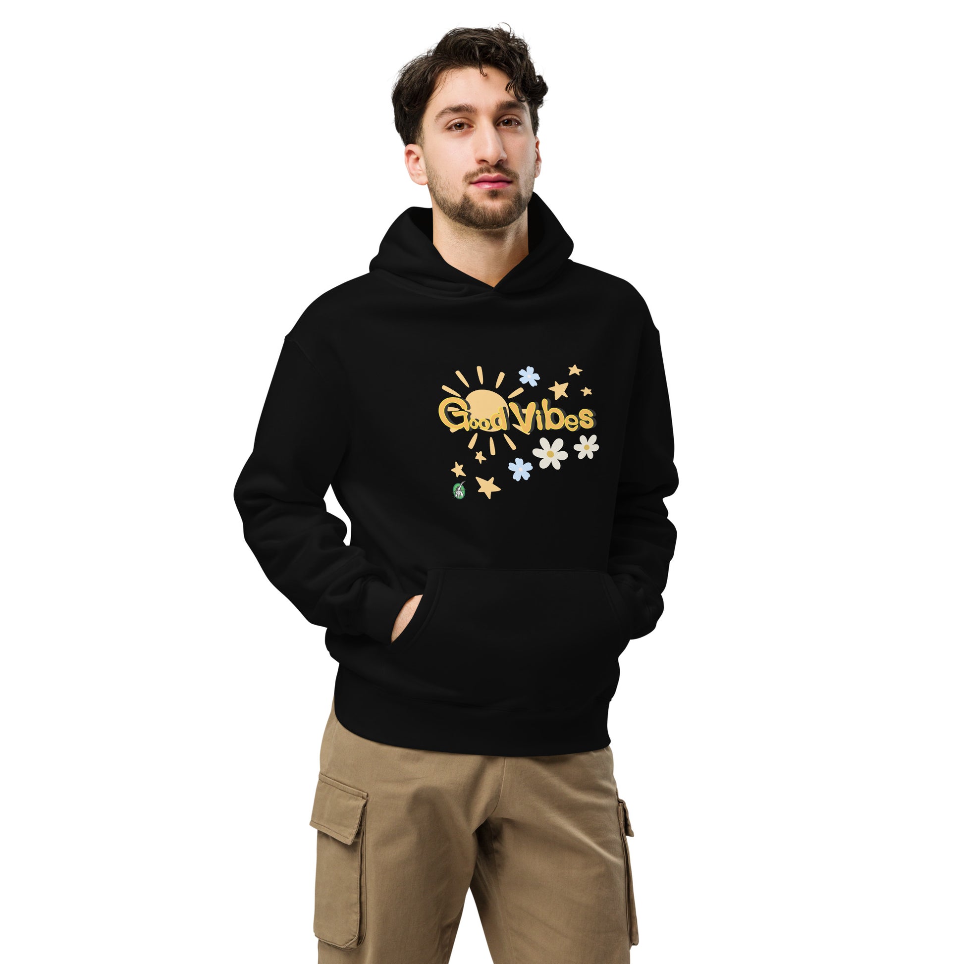 A man standing wearing a black hoodie by Wizard Prints featuring a printed graphic of the sun, flowers, stars and the words, 'Good Vibes'.