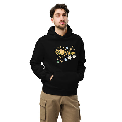 A man standing wearing a black hoodie by Wizard Prints featuring a printed graphic of the sun, flowers, stars and the words, 'Good Vibes'.