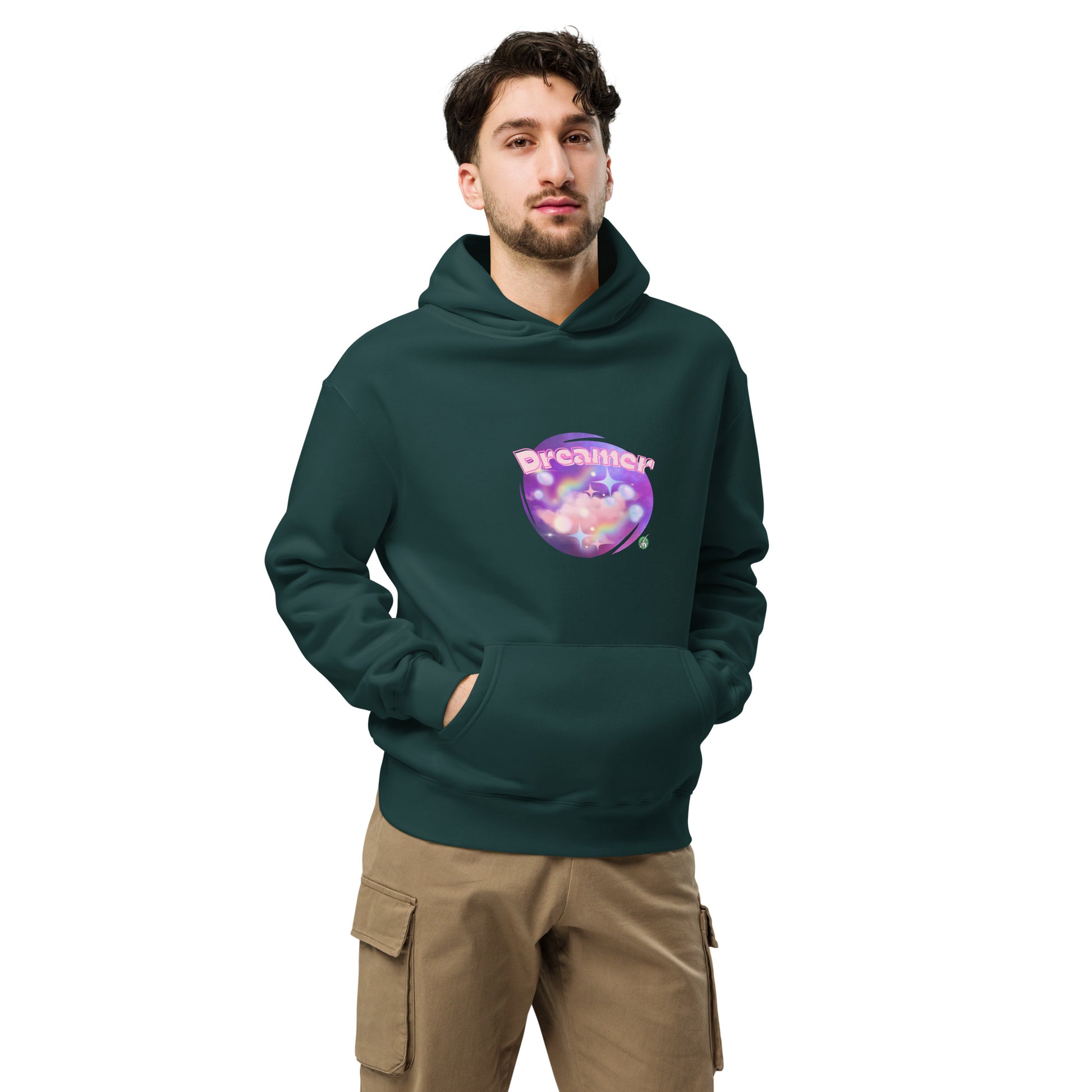 A man standing wearing a pine green hoodie by Wizard Prints featuring a printed graphic of a galaxy background and the word Dreamer on top.