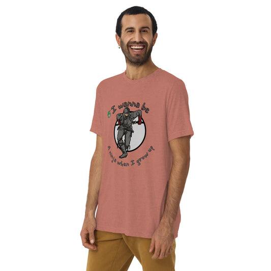 A man standing wearing a mauve t-shirt by Wizard Prints featuring a printed graphic of a ninja with the words, I wanna be a ninja when I grow up.