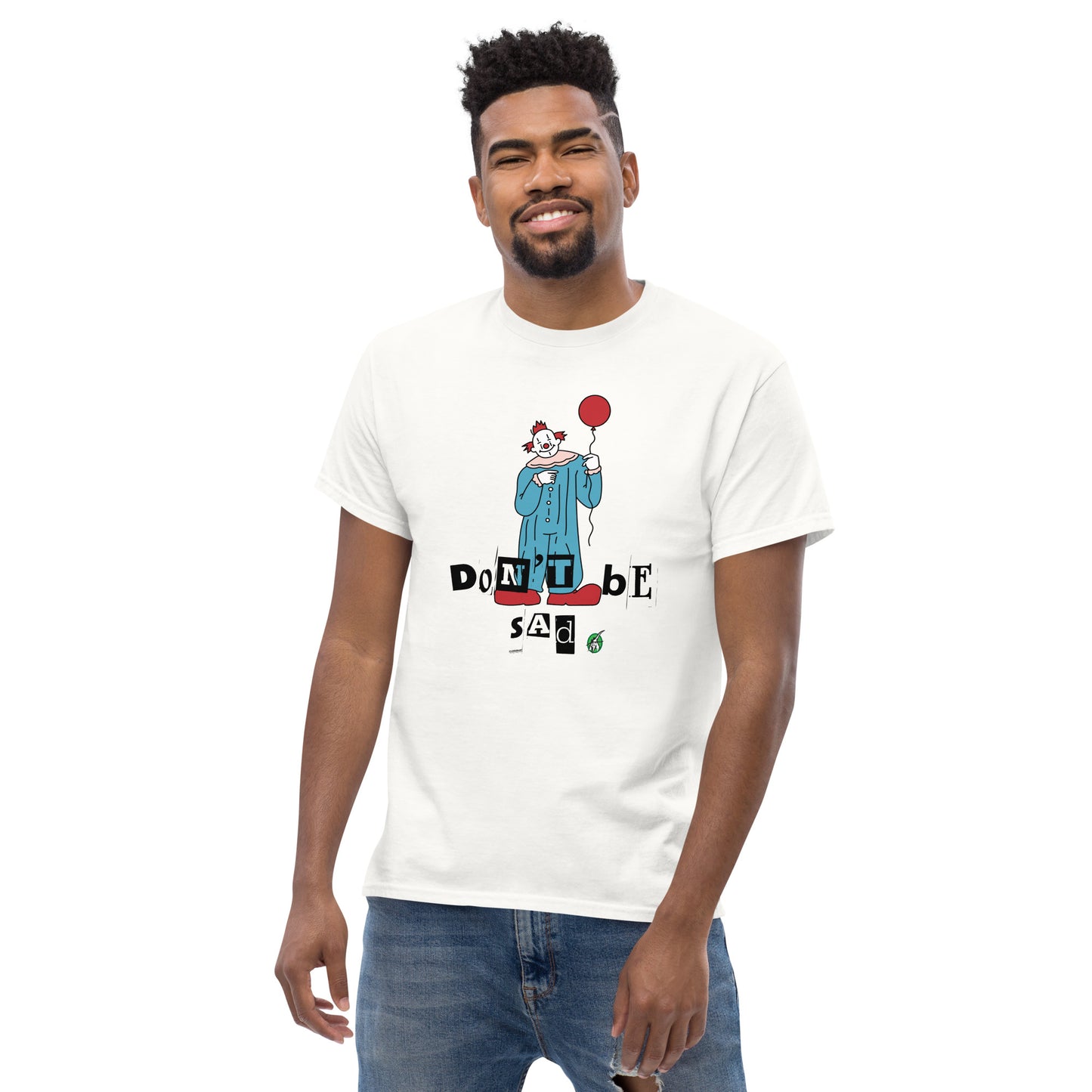 A man standing and wearing a white t-shirt with a printed graphic of a clown holding a balloon with the words, "Don't be sad". Designed by Wizard Prints
