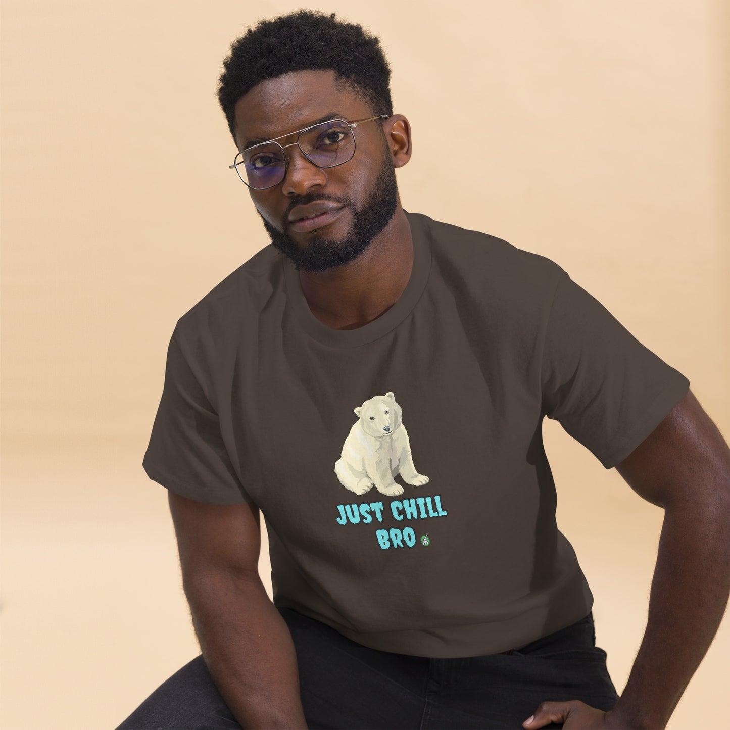 A man sitting and wearing a brown t-shirt with a printed graphic of a bear with the words, 'Just Chill Bro'. Designed by Wizard Prints.