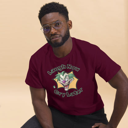A man sitting wearing a maroon t-shirt with a printed graphic of a clown with the words, 'Laugh Now, Cry Later'. Designed by Wizard Prints.