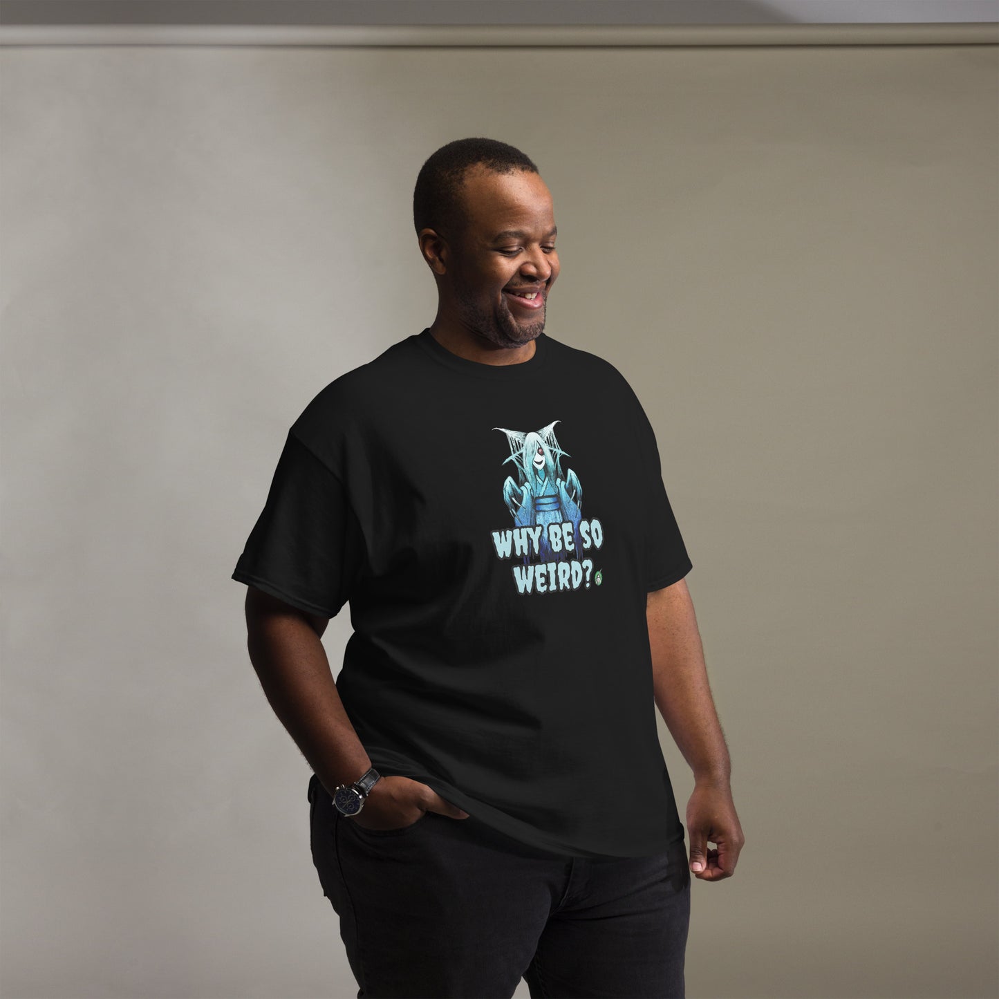 A man standing and wearing a black t-shirt with a printed graphic of a blue ghost girl with the words, 'Why Be So Weird?'. Designed by Wizard Prints.
