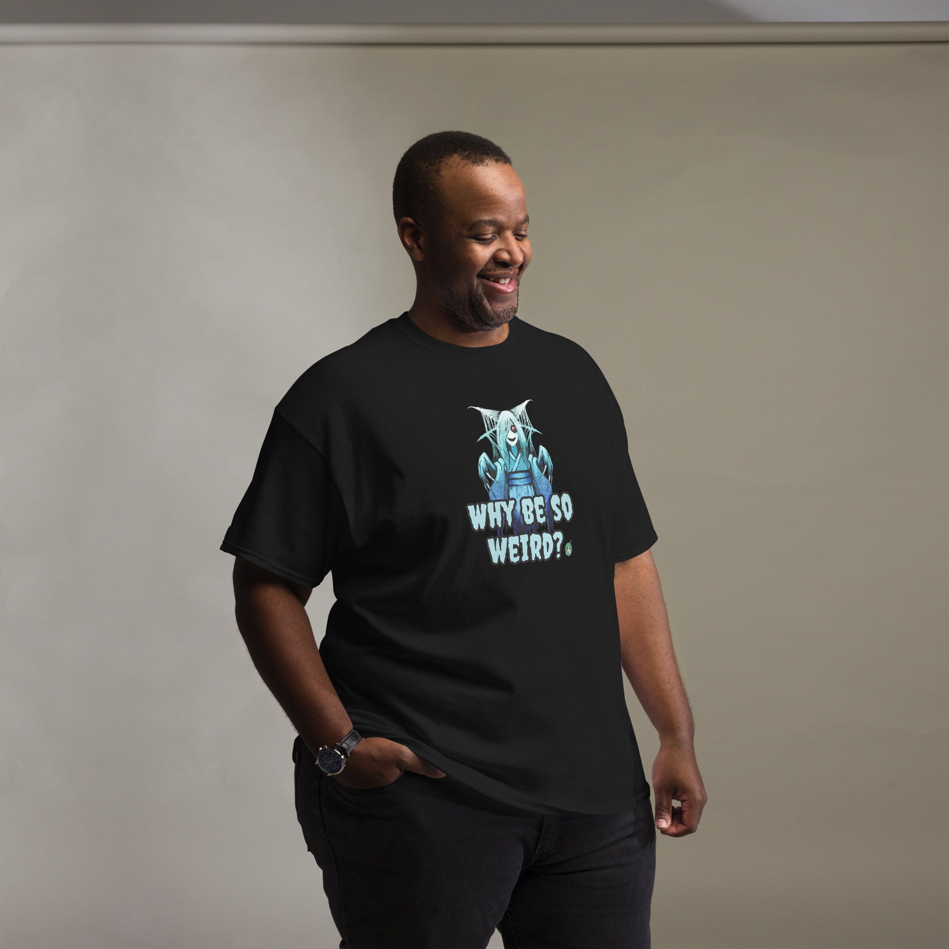 A man standing and wearing a black t-shirt with a printed graphic of a blue ghost girl with the words, 'Why Be So Weird?'. Designed by Wizard Prints.