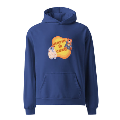 A unisex blue hoodie by Wizard Prints featuring a printed graphic of a cartoon cat and bear wrapped in blankets and the words, Warm & Cozy. 