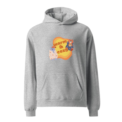A unisex grey hoodie by Wizard Prints featuring a printed graphic of a cartoon cat and bear wrapped in blankets and the words, Warm & Cozy. 