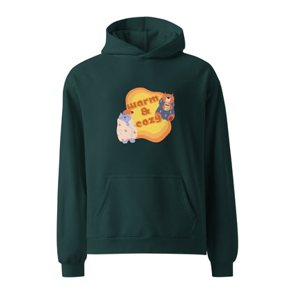 A unisex pine green hoodie by Wizard Prints featuring a printed graphic of a cartoon cat and bear wrapped in blankets and the words, Warm & Cozy. 