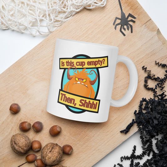 White Wizard Prints funny mug with cartoon monster and 'Is this cup empty? Then Shhh!' text on a wooden board with nuts and spider decorations