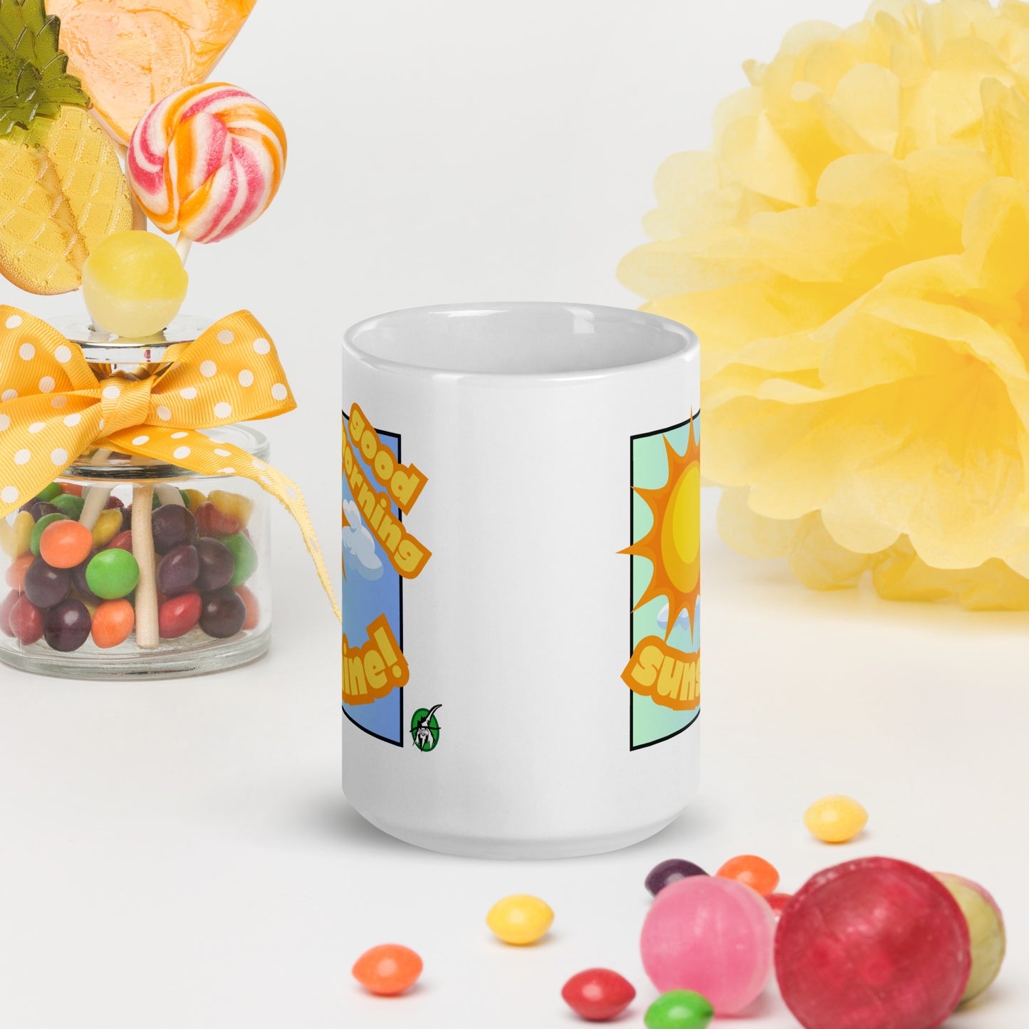White Wizard Prints mug with 'Good morning sunshine' text and sunny graphic, surrounded by candies and flowers on a white background.